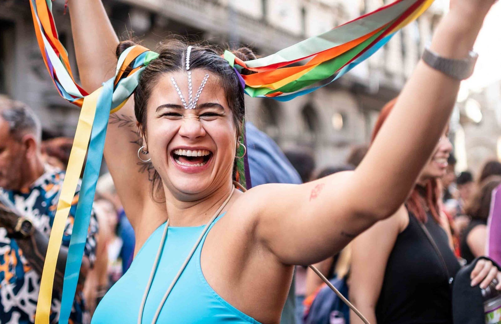 Una persona festeggia al Pride con nastri arcobaleno; Amnesty International per i diritti LGBTQIA+